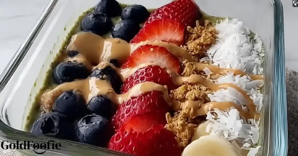 Tropical Smoothie Chia with blueberries, strawberries, coconut, granola, and peanut butter drizzle in a glass container