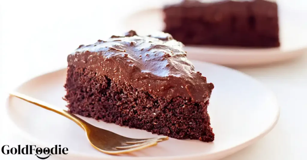 Slice of chocolate chia cake with glossy frosting on white plate