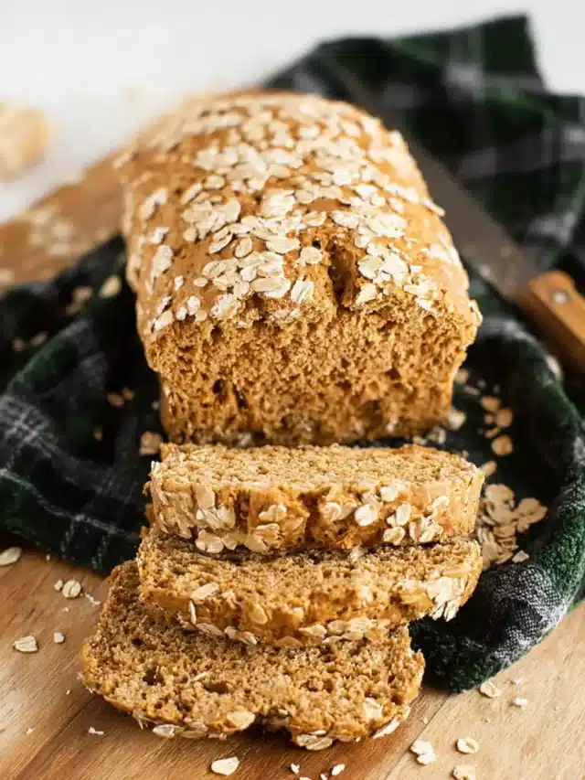 Gluten-free oat bread on cutting board with crumbs.