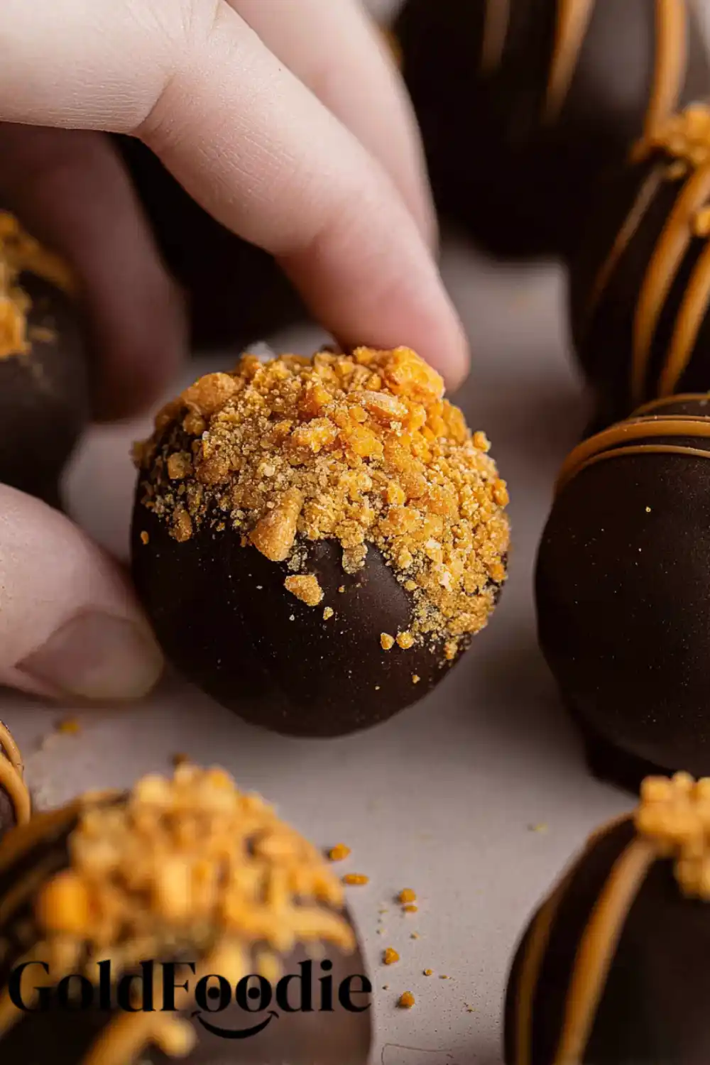 Hand Picking Up a Crushed Butterfinger Topped Truffle Crushed Peanut Butter Chocolate Balls