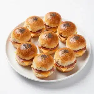 Close-up of freshly baked ham and cheese sliders on a wooden tray.