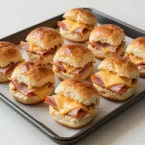 Close-up of garlic butter ham and cheese sliders on a serving tray.