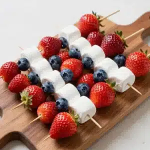 Colorful fruit kabobs featuring strawberries, blueberries, and bananas arranged in red, white, and blue pattern