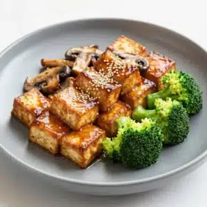 A vibrant mushroom and tofu stir-fry served in a white bowl with colorful vegetables.