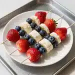 Colorful fruit kabobs featuring strawberries, blueberries, and bananas arranged for a 4th of July celebration