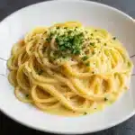 A bowl of creamy leek and garlic spaghetti garnished with fresh parsley.