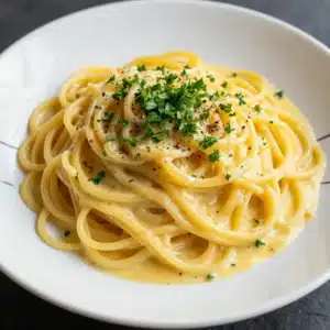 A bowl of creamy leek and garlic spaghetti garnished with fresh parsley.