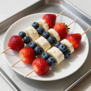 Colorful fruit kabobs featuring strawberries, blueberries, and bananas arranged for a 4th of July celebration