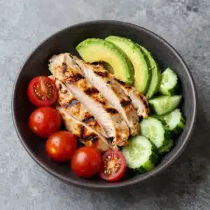 A bowl of healthy avocado chicken salad with fresh vegetables.