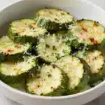 A plate of garlic parmesan roasted zucchini slices, golden and crispy.