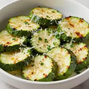 A plate of garlic parmesan roasted zucchini slices, golden and crispy.