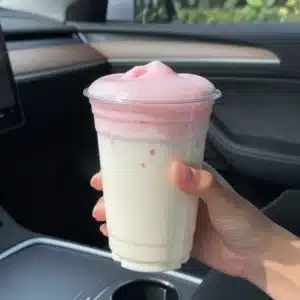 A refreshing iced strawberry horchata chai drink topped with whipped cream and strawberries