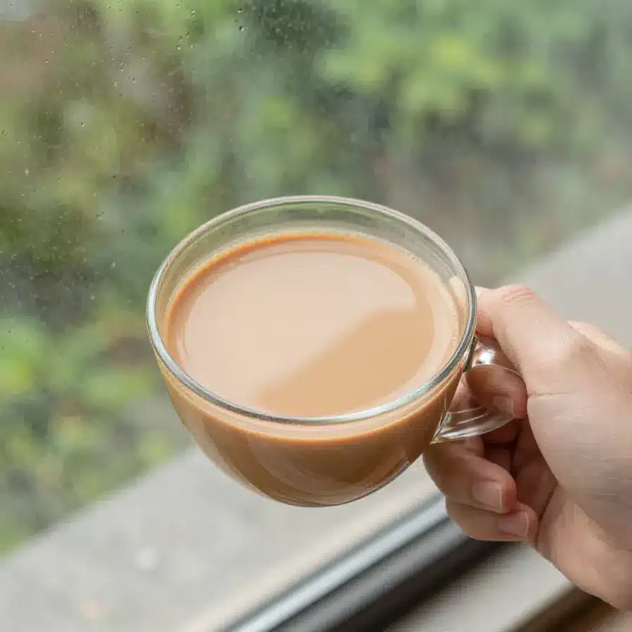 Chai and Rain Captions for Instagram 5 A steaming cup of chai placed by a window with raindrops on the glass.
