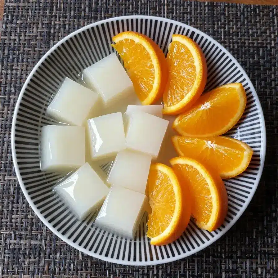 Almond Jello Recipe: Easy and Refreshing Chinese Dessert 5 A bowl of almond jello topped with fresh fruit and mint leaves
