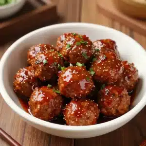 Close-up of sweet chili meatballs served in a crockpot, garnished with fresh parsley.
