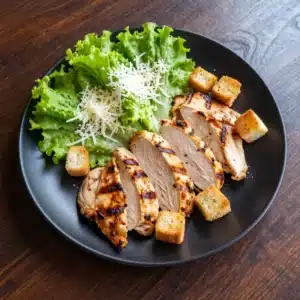 A vibrant healthy Caesar salad topped with grilled chicken, romaine lettuce, and croutons