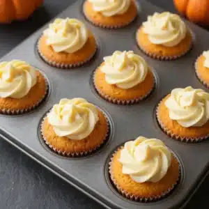 A freshly baked pumpkin cream cheese swirl muffin on a wooden table