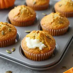 Freshly baked pumpkin cream cheese muffins on a wooden table