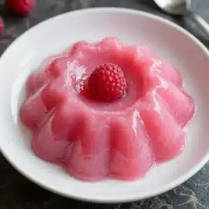 A bowl of sugar-free keto jello whips topped with whipped cream and berries