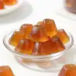 Close-up of homemade tea gelatin collagen gummies shaped like small cubes on a white plate.