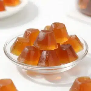 Close-up of homemade tea gelatin collagen gummies shaped like small cubes on a white plate.