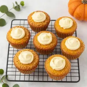 Freshly baked pumpkin cream cheese muffins with a golden crumb topping on a white plate