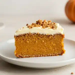 A moist pumpkin cake topped with smooth cream cheese frosting and a light dusting of cinnamon.