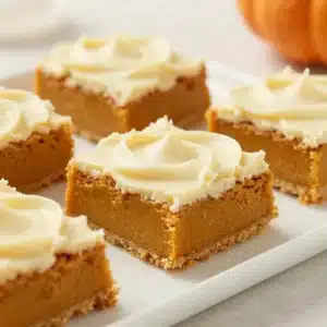 Homemade Paula Deen pumpkin bars topped with creamy frosting on a white plate