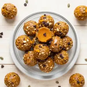 Homemade pumpkin protein energy balls rolled in oats and seeds on a white plate